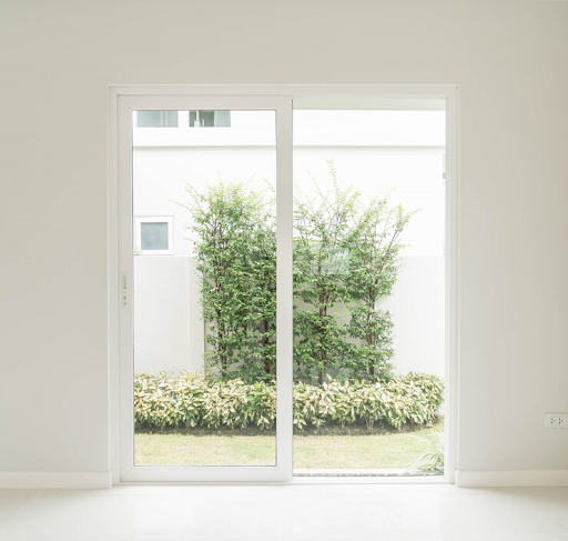 Porte en verre coulissante donnant sur un jardin verdoyant